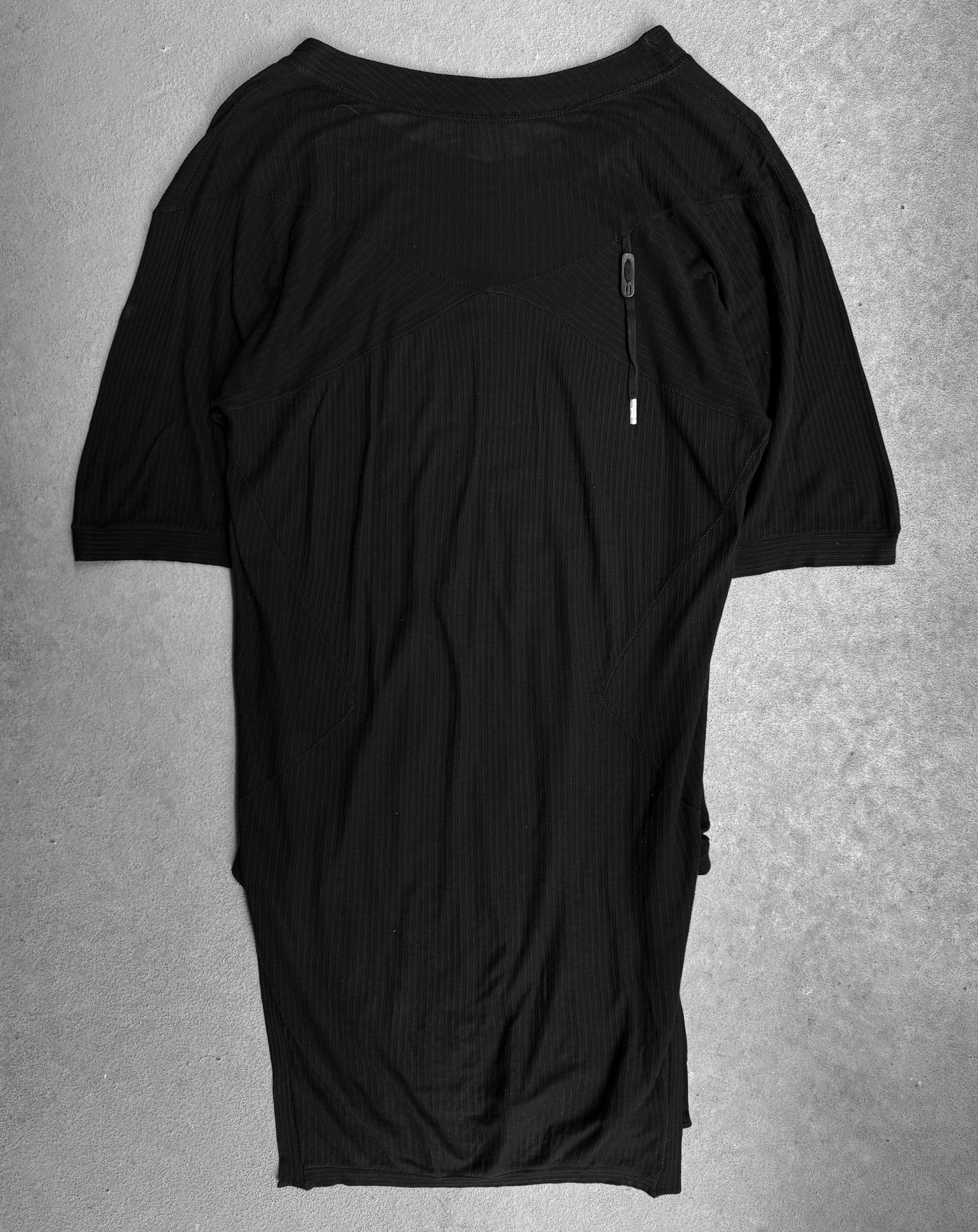A worn, wrinkled Boris Bidjan Saberi SS15 ‘TS2-F0407’ ribbed raglan T-shirt by DRIEW in black, size M, featuring a zippered pocket on the upper left chest, is laid flat on a light textured surface.