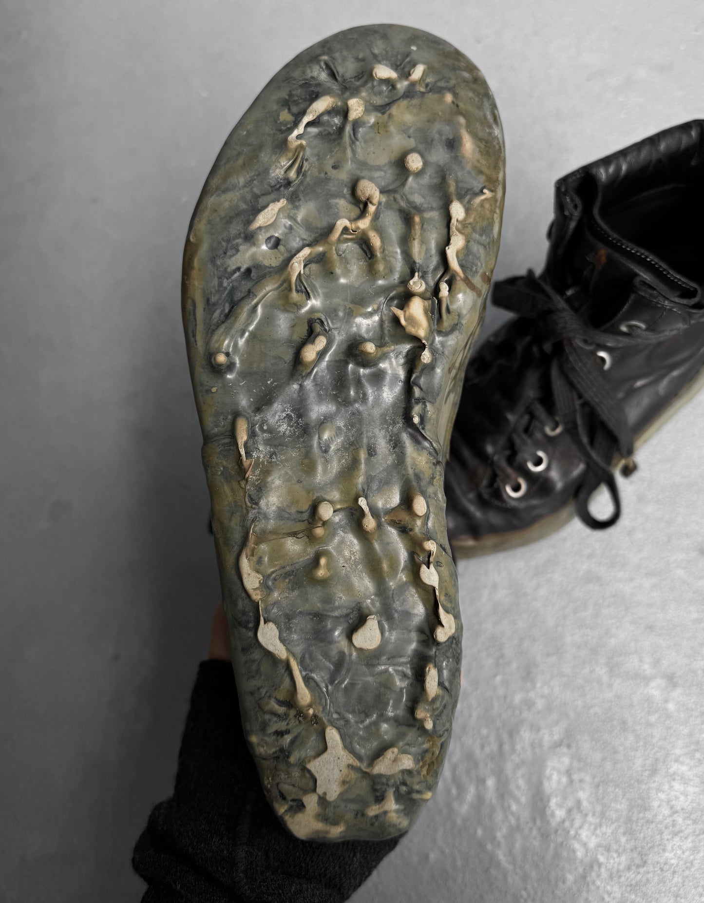 A close-up of the sole of a worn DRIEW Carol Christian Poell ‘AM/2685P ROOMS-PTC/12’ Object-dyed Kangaroo Leather Titanium Prosthetic U-sole Drip Sneaker, Size 6, with hardened beige drips, shown against a light gray background.