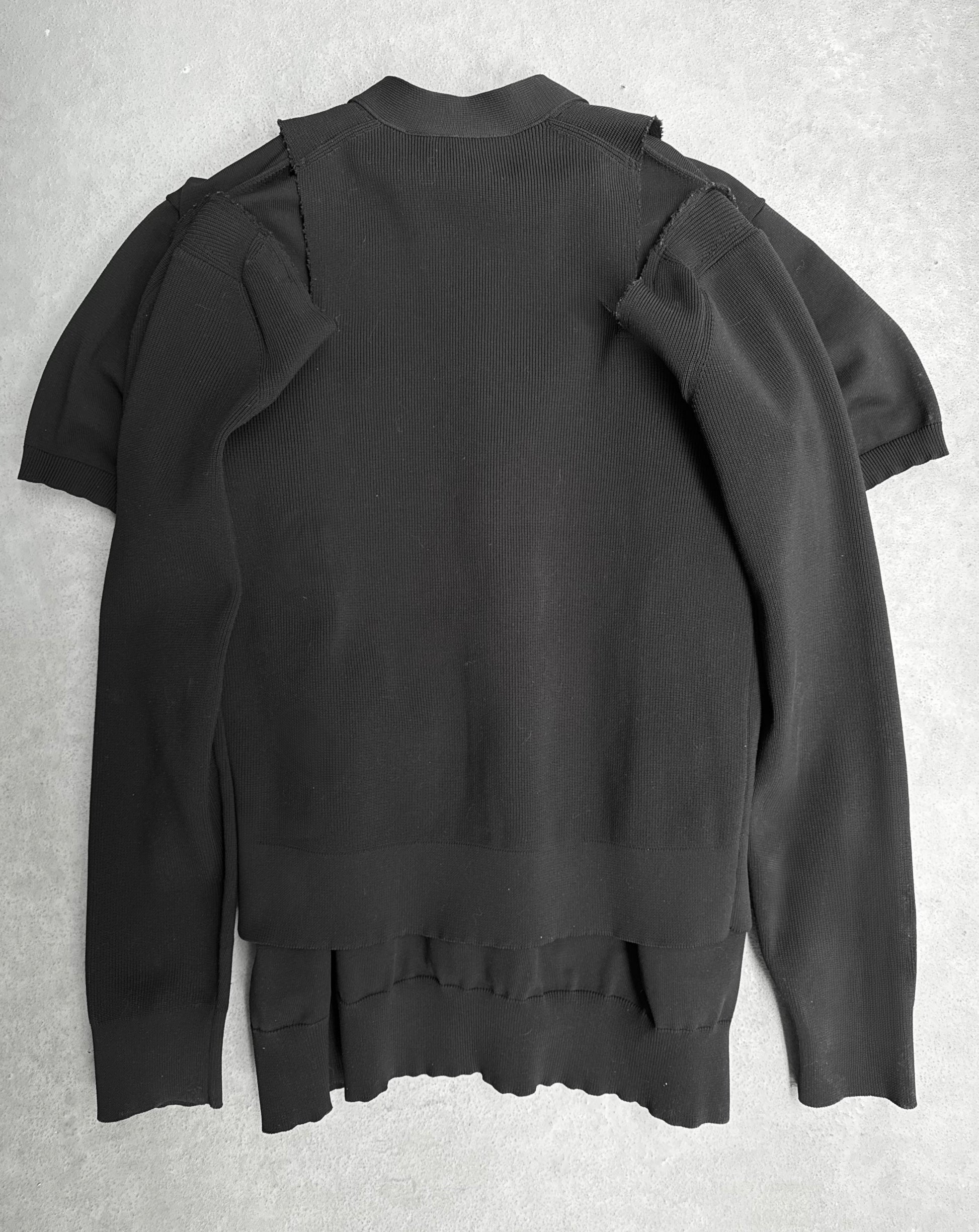 The COMME des GARÇONS SS19 Deconstructed 2-in-1 Cardigan in black features avant-garde fashion with overlapping layers, exposed seams on a gray surface, and seemingly unfinished edges, capturing the unique style often found at Dover Street Market.