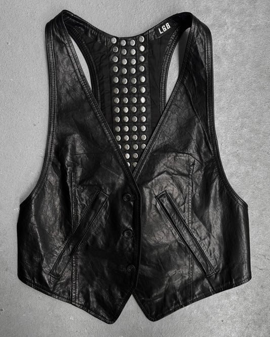 The L.G.B Early 00s Calfskin Leather Studded Mini-vest, in black, features front buttons, two slanted pockets, and a studded back panel inspired by Japanese fashion, shown laid flat on a gray surface.