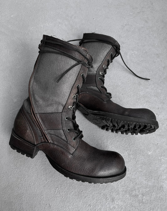 The Kyoji Maruyama Early 00s Brown Tornado Zip Combat Boots rest on a gray surface, showcasing a two-tone sheepskin leather design with darker hues at the bottom. Featuring high tops, lace-up details, intricate stitching, and thick textured soles, they epitomize Japanese fashion flair.