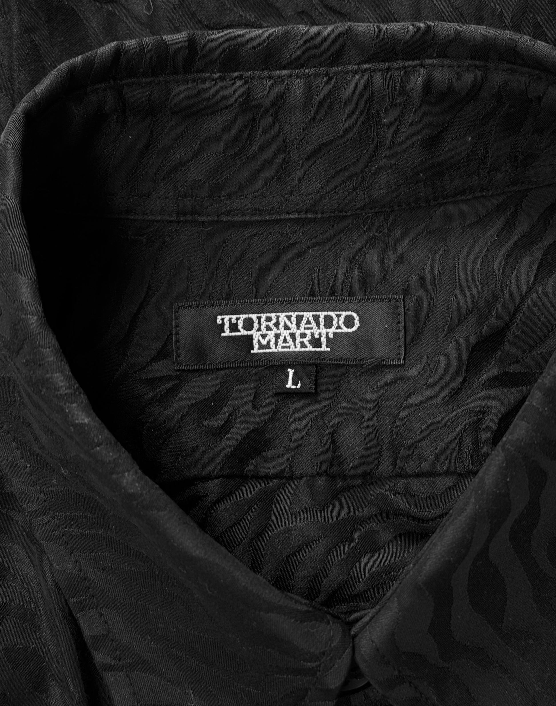 A close-up of a Tornado Mart Early 00s Zebra Imprint Button-up Shirt features a subtle, wavy pattern symbolic of Japanese mens fashion. The inside collar sports the TORNADO MART label in bold white letters with size L beneath, showcasing the brands luxurious fabrics and style.