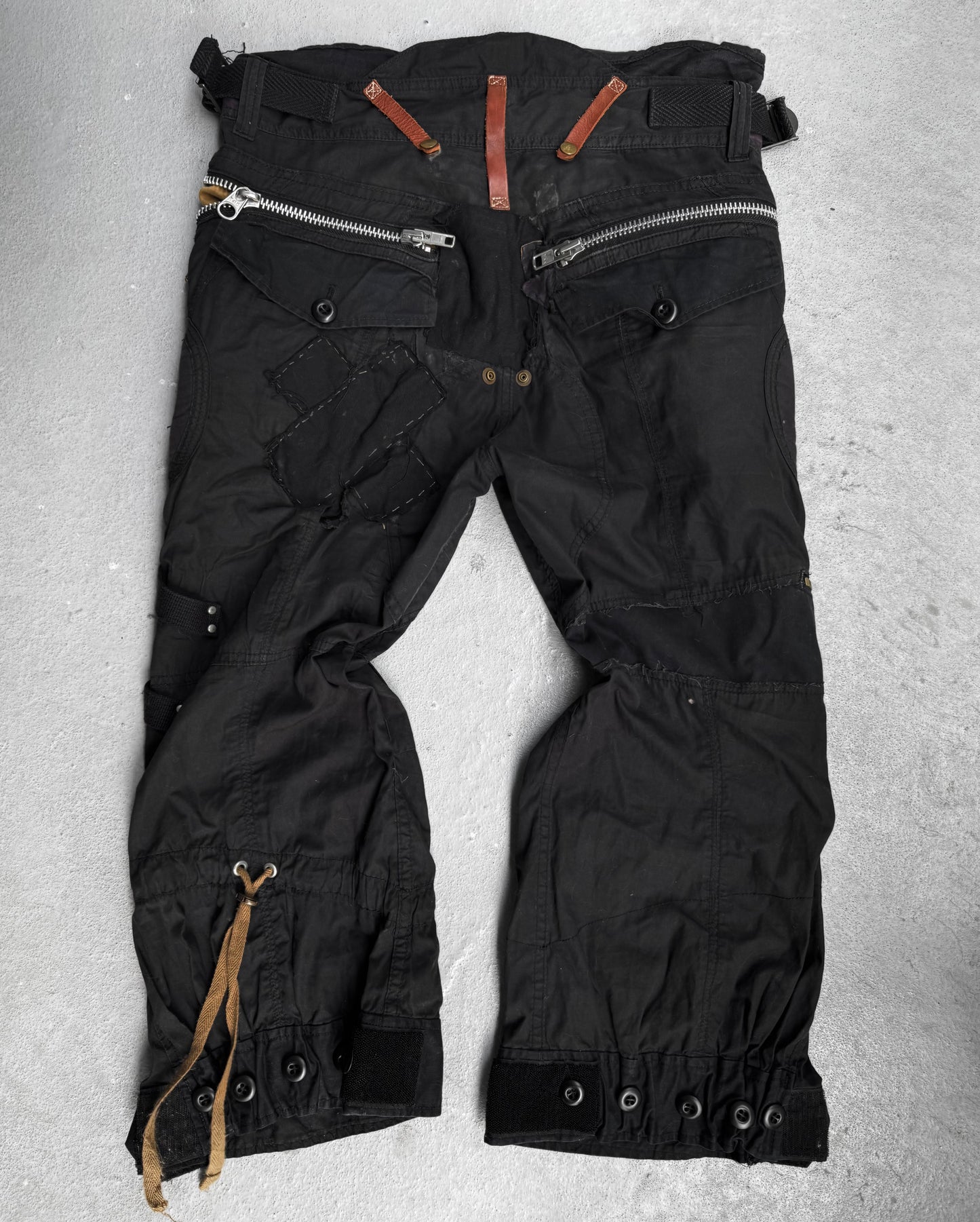 L.G.B Early 00s Pilot Cargo Capris in black, featuring rugged used condition, visible stitching, large silver zippers with brown leather pulls, drawstring at one cuff, multiple panels and buttons. Size: US 32 Waist.