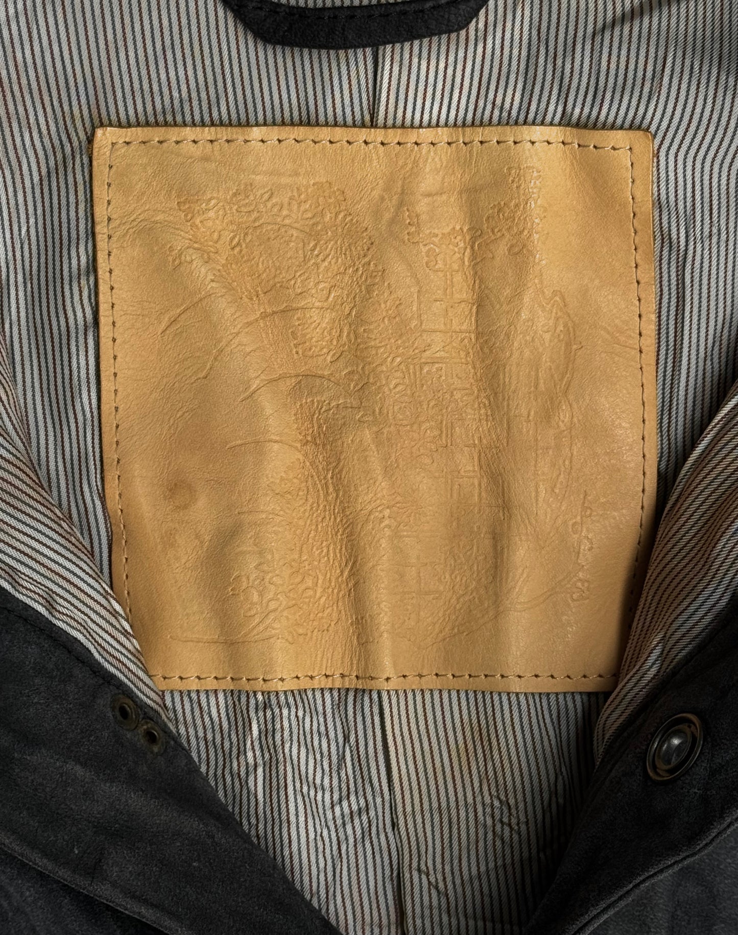 A close-up of a tan nubuck leather patch stitched onto striped fabric inside the Kyoji Maruyama Early 00s Washable Wrinkle Nubuck Leather Shirt highlights the subtle textures and fine Japanese craftsmanship of this designer piece.