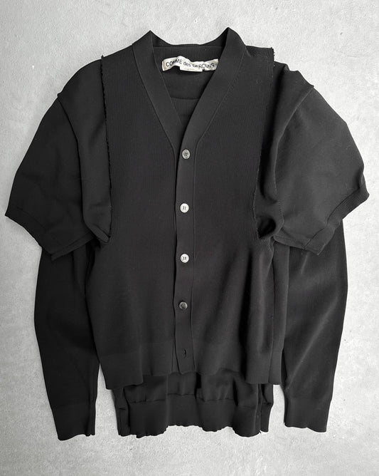 The COMME des GARÇONS SS19 Deconstructed 2-in-1 Cardigan, an avant-garde black layered piece combining a ribbed button-up vest with a short-sleeve shirt, is styled on a gray background, reflecting the edgy fashion of Dover Street Market and COMME des GARÇONS.