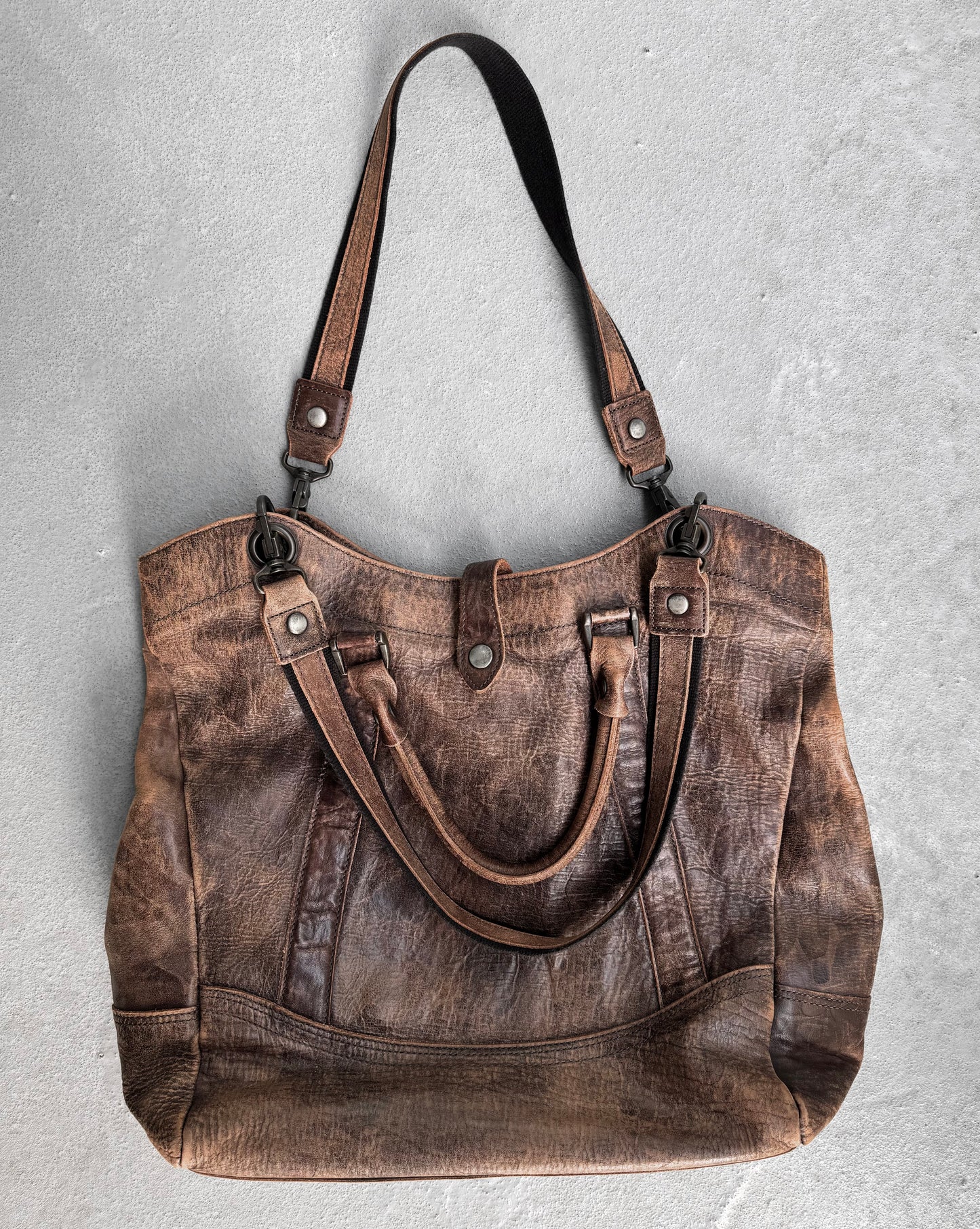 The alfredoBANNISTER Early 00s Faded Brown Cowhide Tote Bag features dual handles, a detachable shoulder strap, and metal hardware on a textured gray backdrop. Crafted from exquisite Japanese leather, it showcases rustic charm with visible stitching and contemporary design by alfredoBANNISTER.