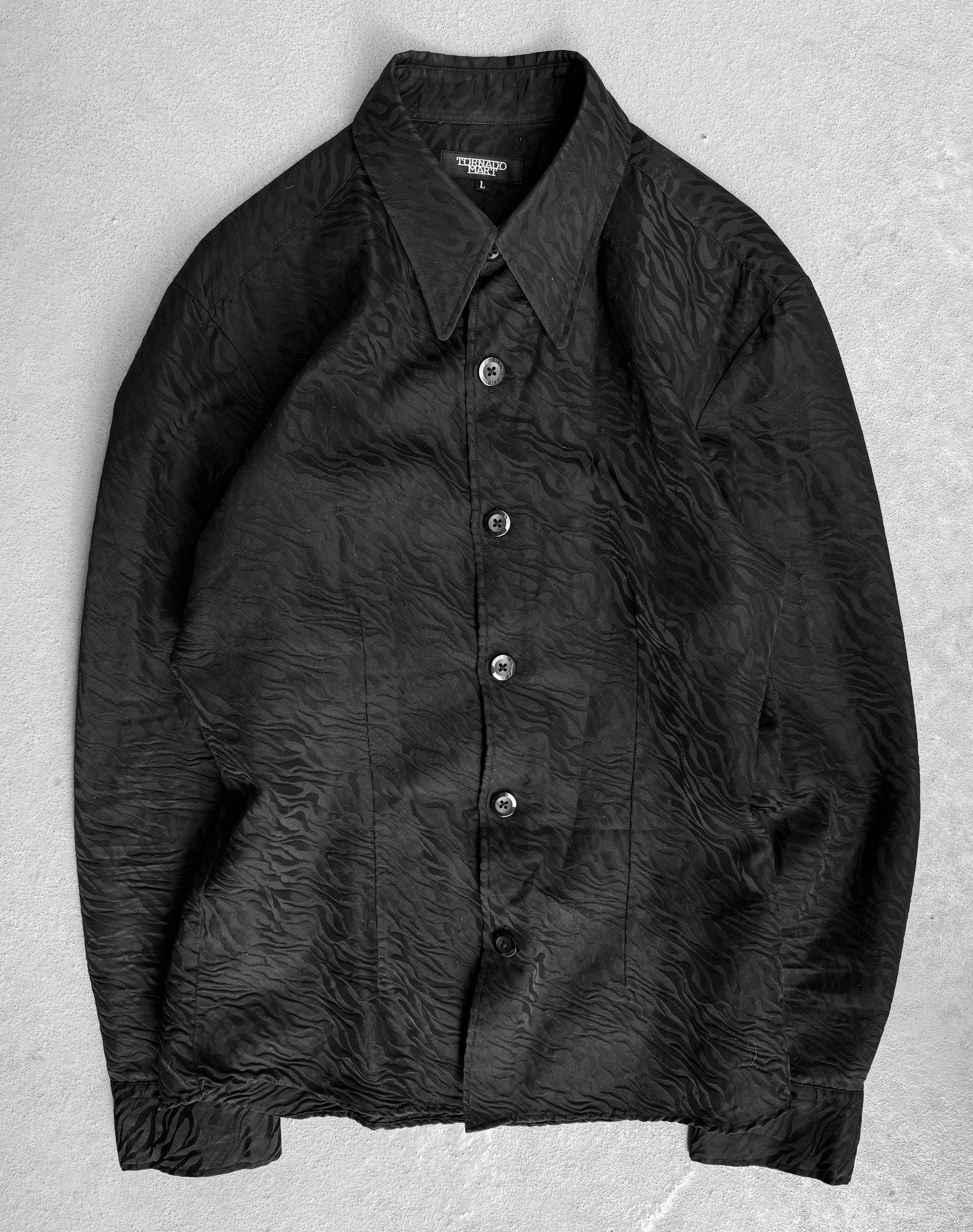 The Tornado Mart Early 00s Zebra Imprint Button-up Shirt is a black long-sleeve collared design with a wrinkled texture, laid flat on light gray. It features five visible buttons and embodies the luxurious fabric style reminiscent of Japanese mens fashion by Tornado Mart.