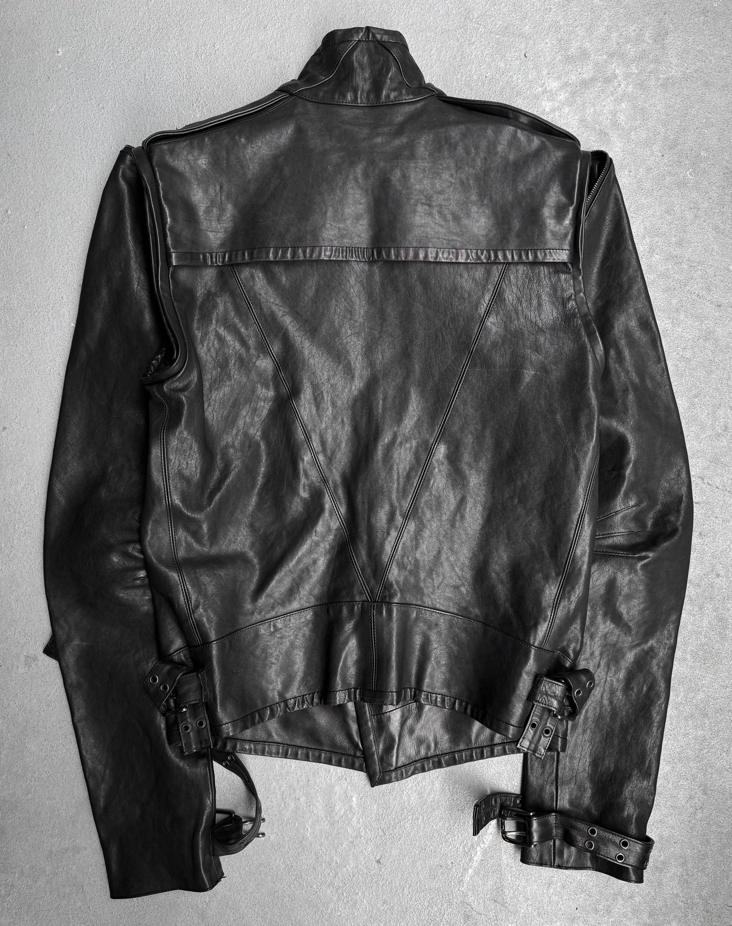 The Gareth Pugh AW09 Detachable Sleeves Horse Leather Riders Jacket is shown laid flat, back view, on a light surface. It features detailed stitching, shoulder epaulets, and adjustable waist and wrist belts—a signature Gareth Pugh design.