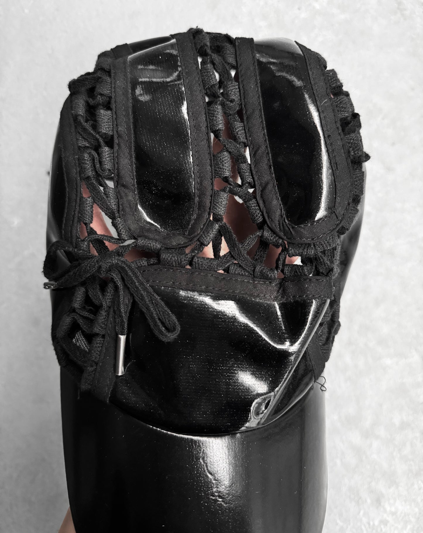 Close-up of KTZ (Kokon to Zai) Late 00s Lace Through Aviator Cap by London-based Konko to Zai, showcasing intricate strings revealing glimpses of skin. The glossy finish contrasts with matte elements, embodying their signature East meets West style.