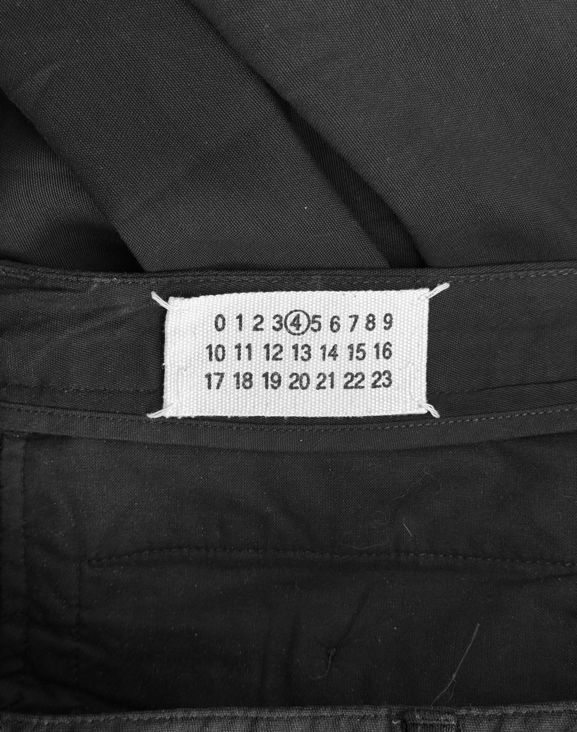 Maison Martin Margiela presents avant-garde fashion with deconstructionist techniques, featuring numbers 0 to 23. Their Early 00s Double Pleated Dress Pants have the number 11 circled and sewn into the black fabric.