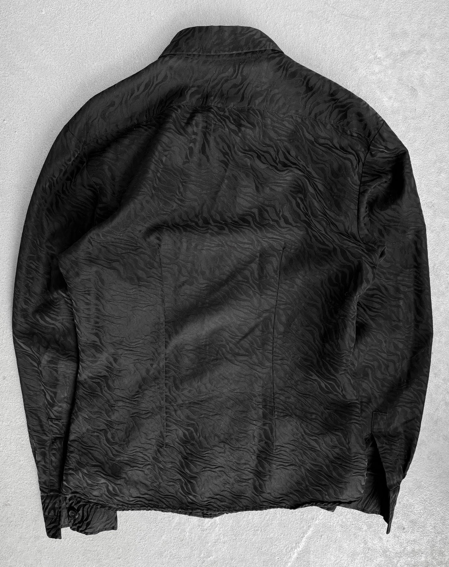 The Tornado Mart Early 00s Zebra Imprint Button-up Shirt, a black textured piece with subtle wave patterns on light gray, embodies the elegance of Japanese mens fashion. Laid flat to reveal its back view, the collar and cuffs are crafted from luxurious fabrics true to Tornado Marts style.