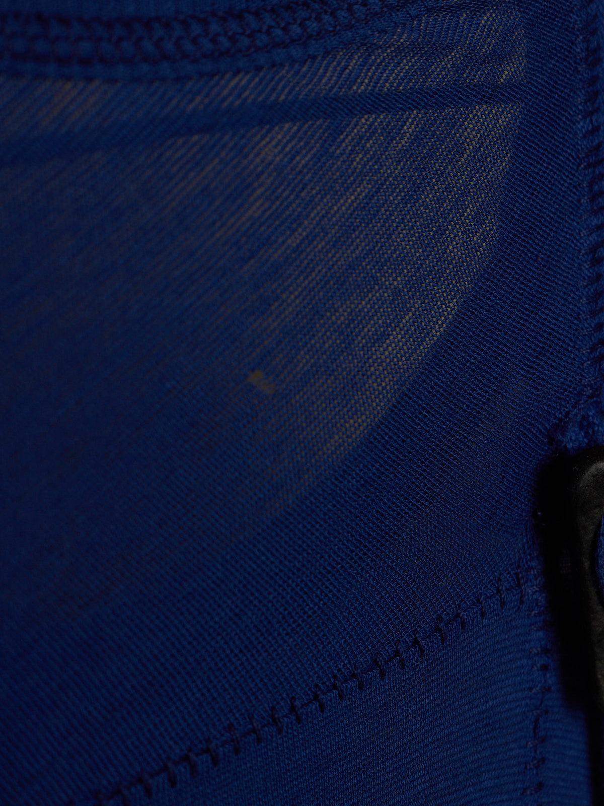 Close-up of a dark blue mesh fabric with visible stitching and a small black hook or fastener on the right side.