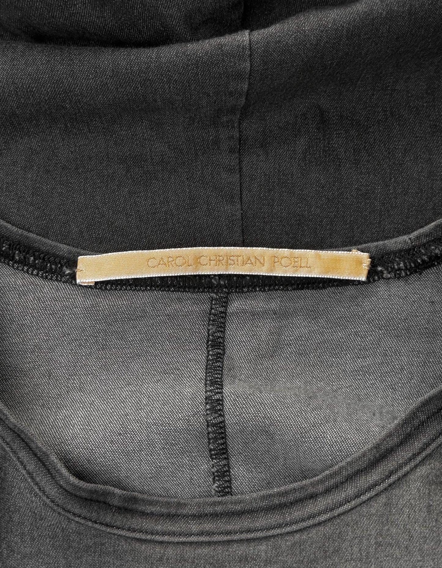 Close-up of a label on a black garment with 'Caroline Constas Poell' branding.