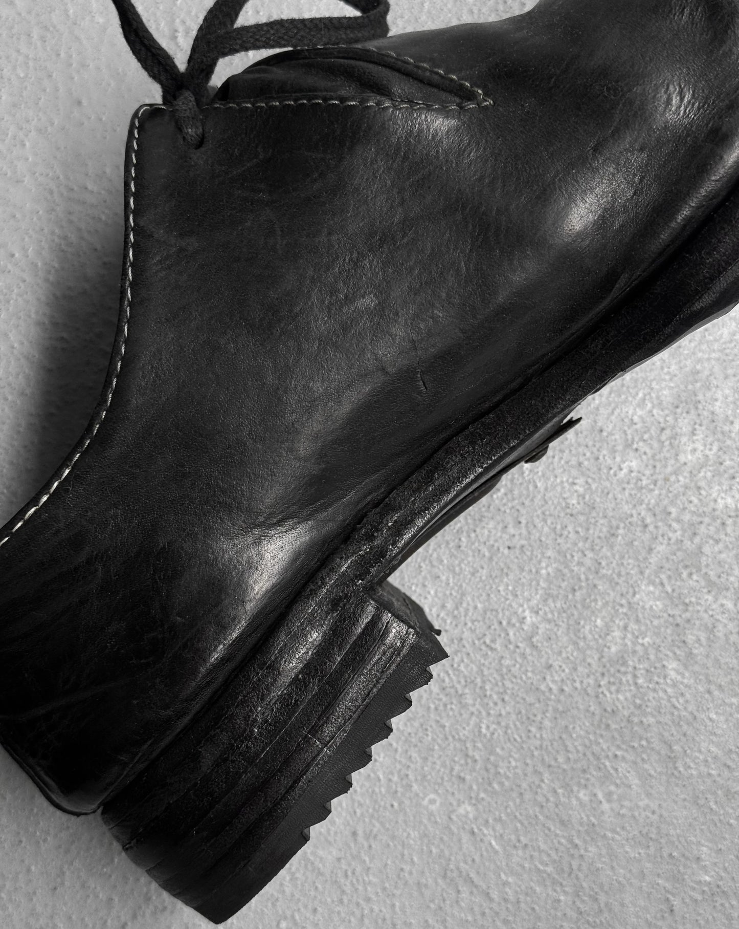 Black leather boot on a light gray background