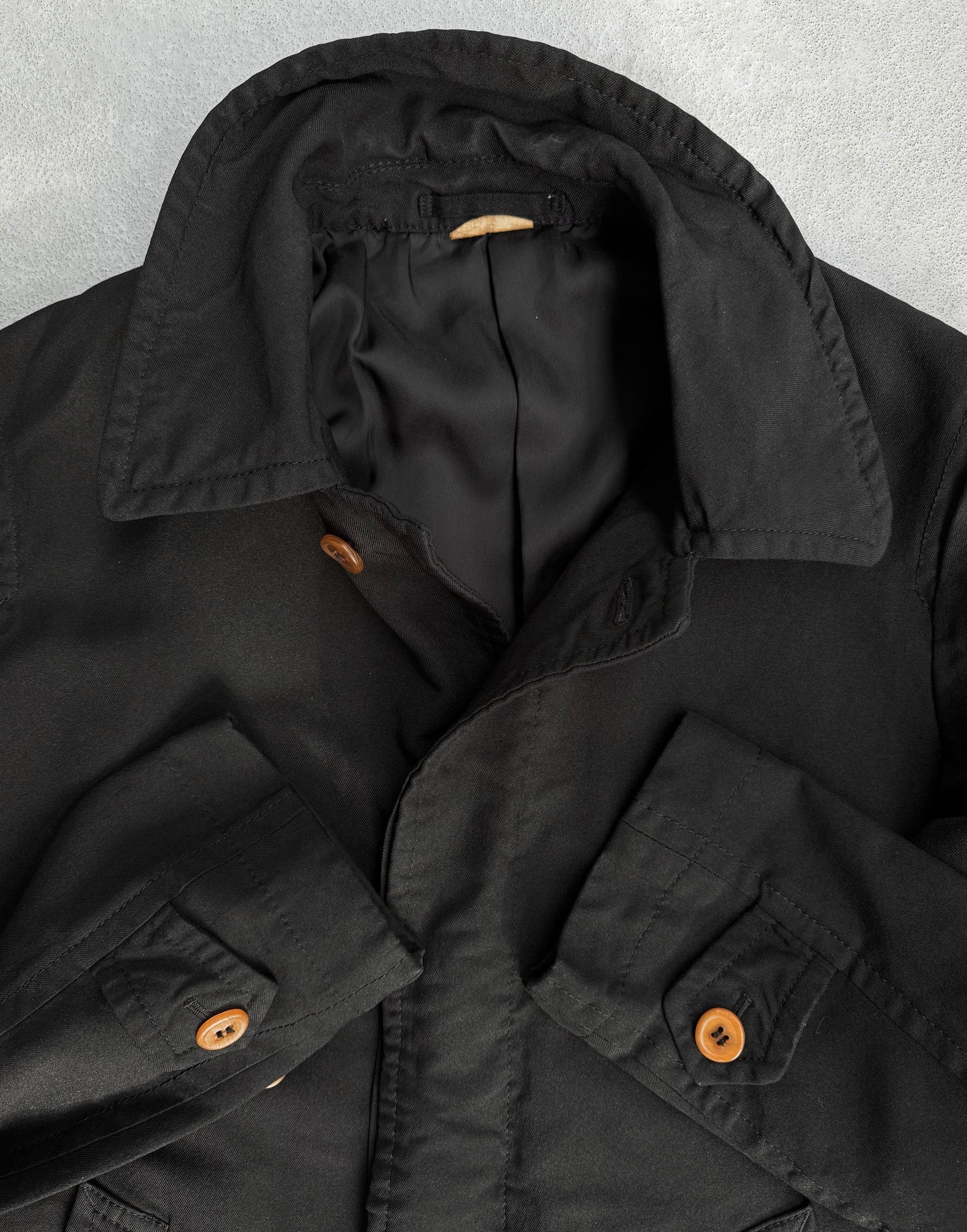 The COMME des GARÇONS HOMME DEUX Early 00s Reversible Button-up Coat, embodying avant-garde fashion with a wide collar and brown buttons, is displayed on a light gray surface. Its visible stitching on sleeves and pockets aligns with the classic COMME des GARÇONS aesthetic.