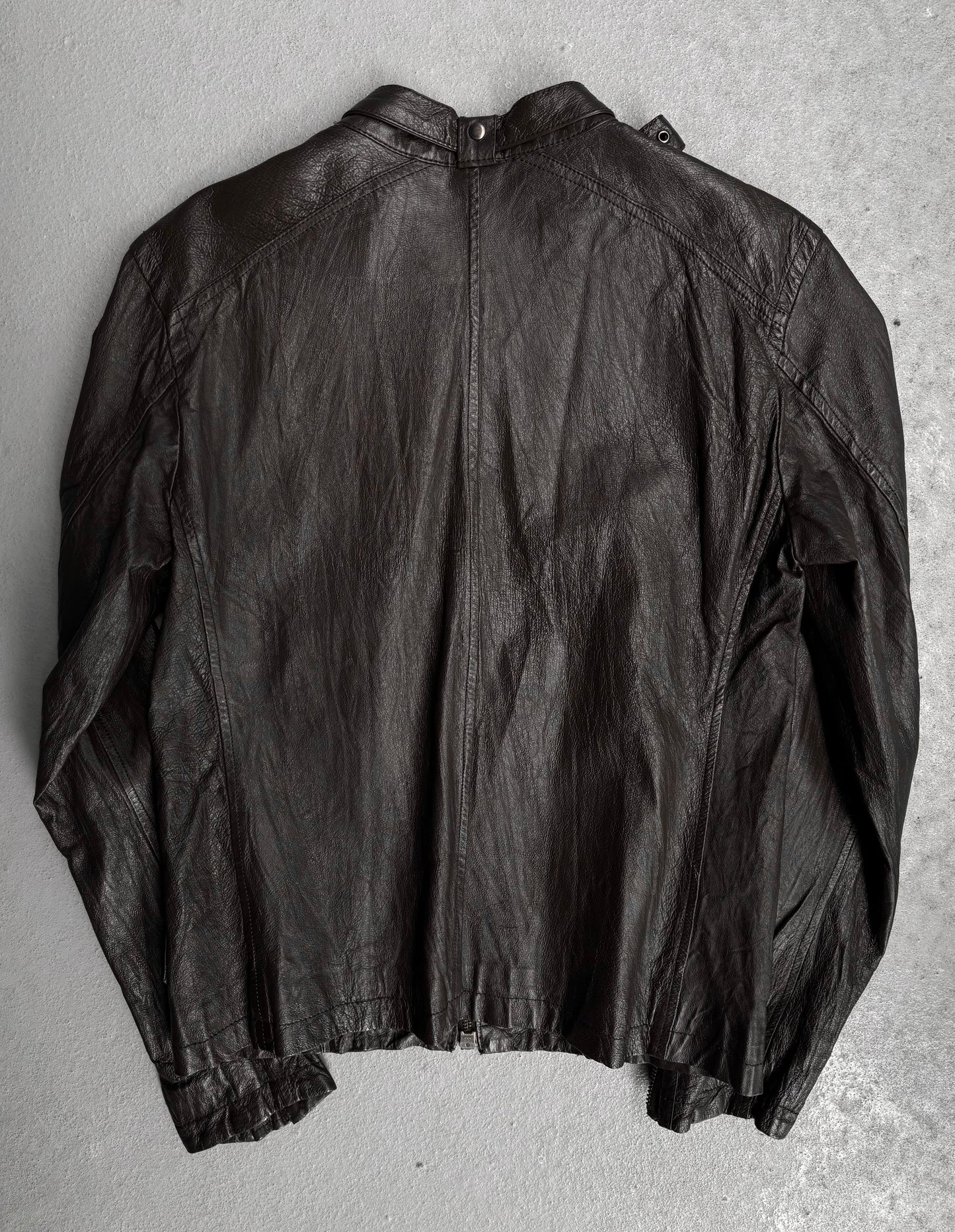 The Jackrose Early 00s Multi-pockets Pig Skin Leather Rider Jacket is shown laid flat, back view, on a light gray surface. Slightly worn with visible creases and a snap neck closure, this classic black biker piece channels Tokyo street fashion.