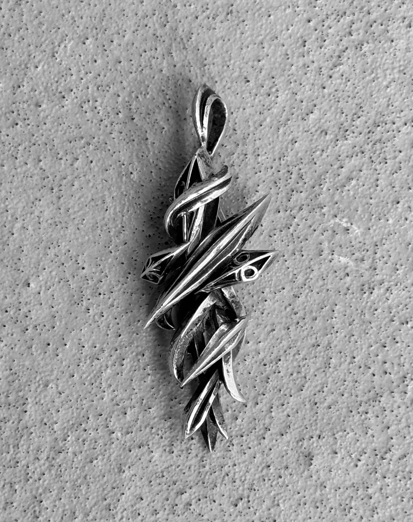 The M’s COLLECTION (BLESS) Early 00s Silver Arabesque Cross Pendant features an intricate design with intertwining elements and smooth, pointed tips. This polished abstract piece by BLESS represents the elegance of Cable Jewellery and echoes themes of sustainability.