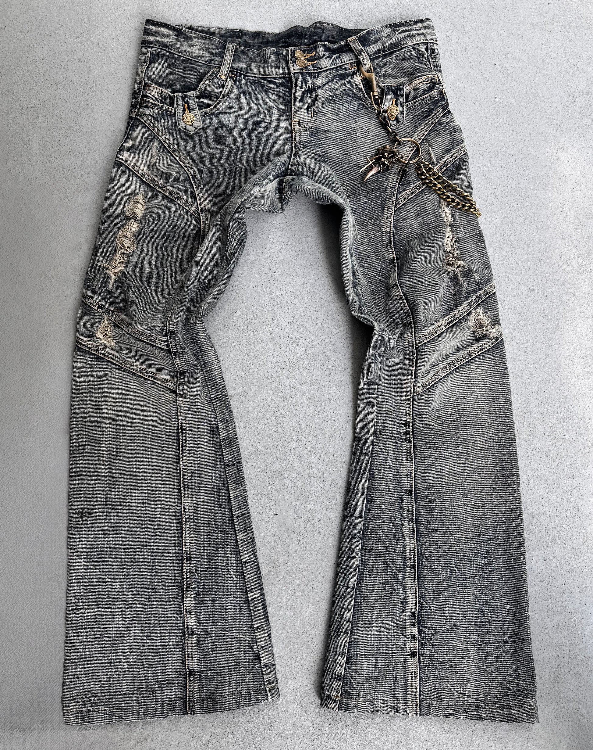 Tornado Mart Early 00s Faded Blue Distressed Flare Bootcut Denim jeans with visible creases, rips, and a metal chain clipped to a front belt loop add a punk streetwear edge. Laid flat on a light surface.