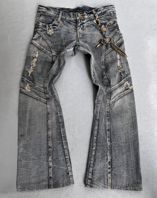 Tornado Mart Early 00s Faded Blue Distressed Flare Bootcut Denim jeans with visible creases, rips, and a metal chain clipped to a front belt loop add a punk streetwear edge. Laid flat on a light surface.