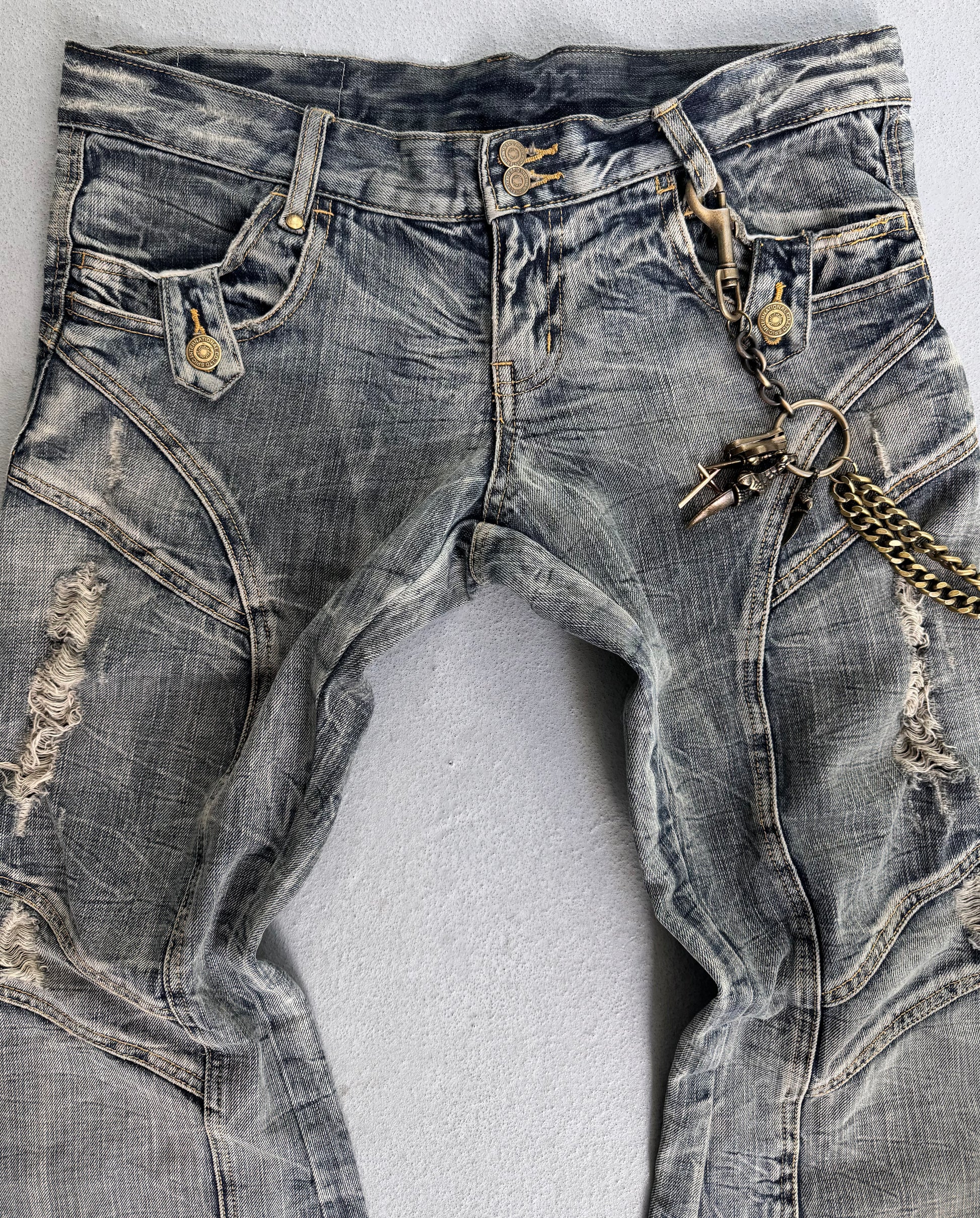 Tornado Mart Early 00s Faded Blue Distressed Flare Bootcut Denim features visible seams, button details, and a gold chain with keys on the right belt loop—a bold punk streetwear piece reminiscent of classic Tornado Mart style.
