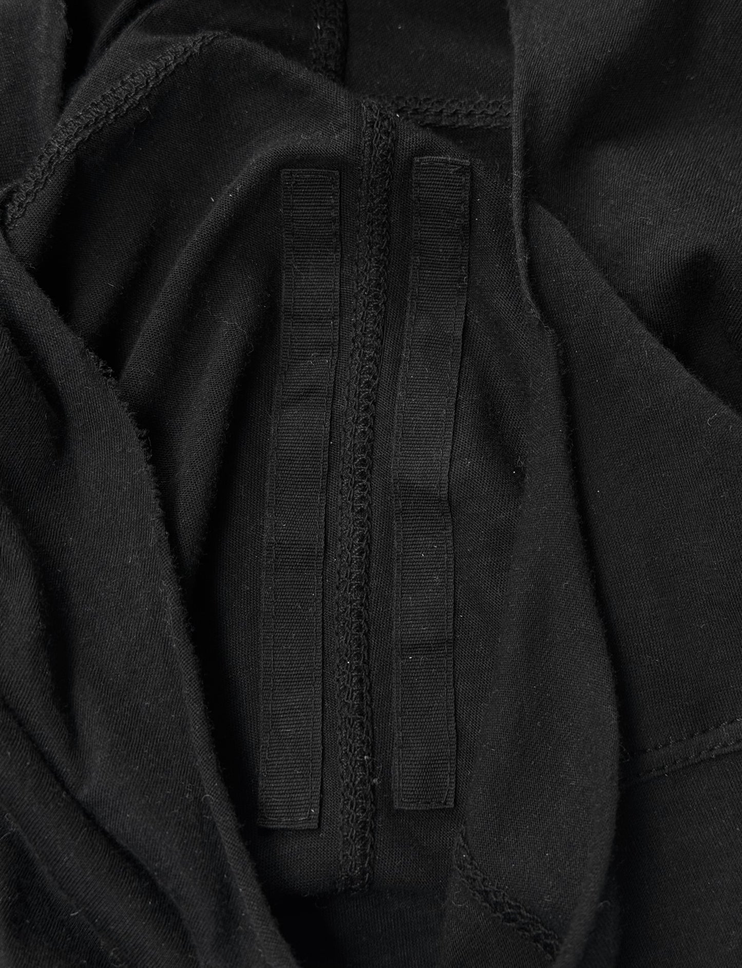 A close-up of black fabric with two parallel black velcro strips, inspired by Rick Owens DRKSHDW AW24 “PORTERVILLE” Geometric Level Long-sleeves, nodding to the brand’s iconic avant-garde aesthetic.