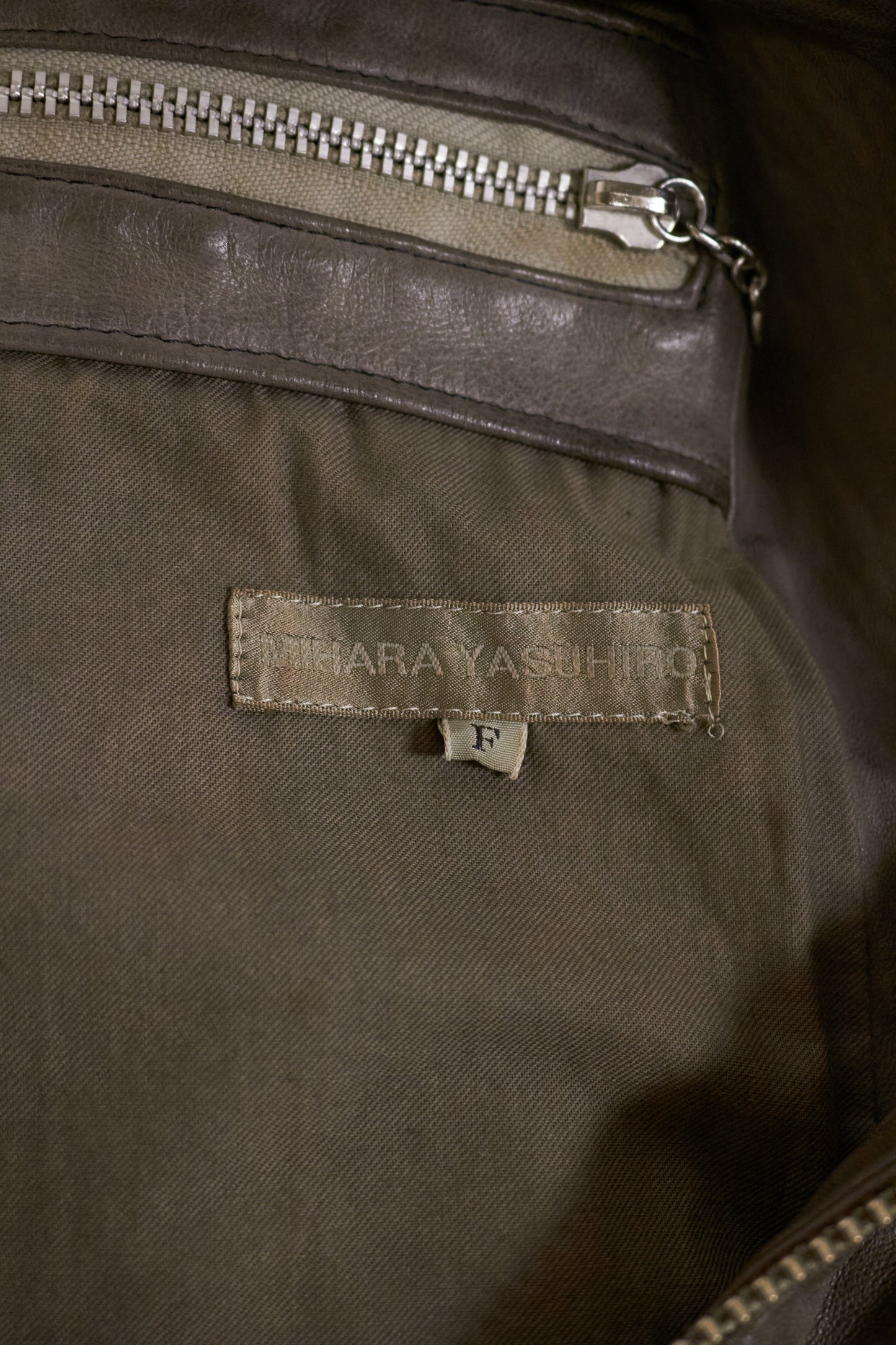 Close-up of a brown fabric with a brand label and zipper.