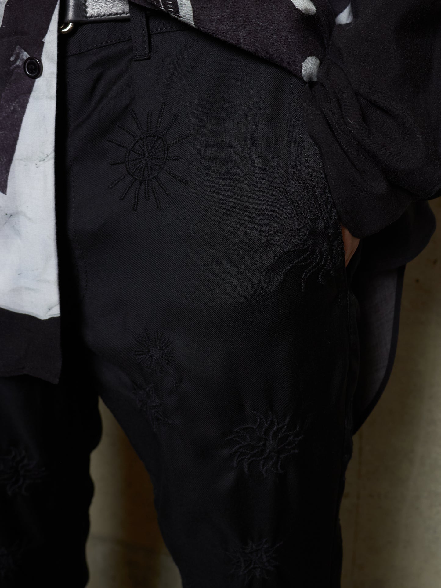 Black pants with embroidered design on a neutral background