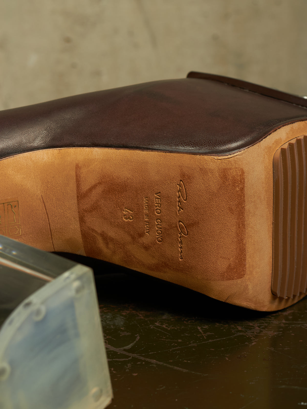 Close-up of the sole of a dark brown leather boot, showing the tan Vero Cloro rubber outsole and embossed branding, resting on a dark surface.