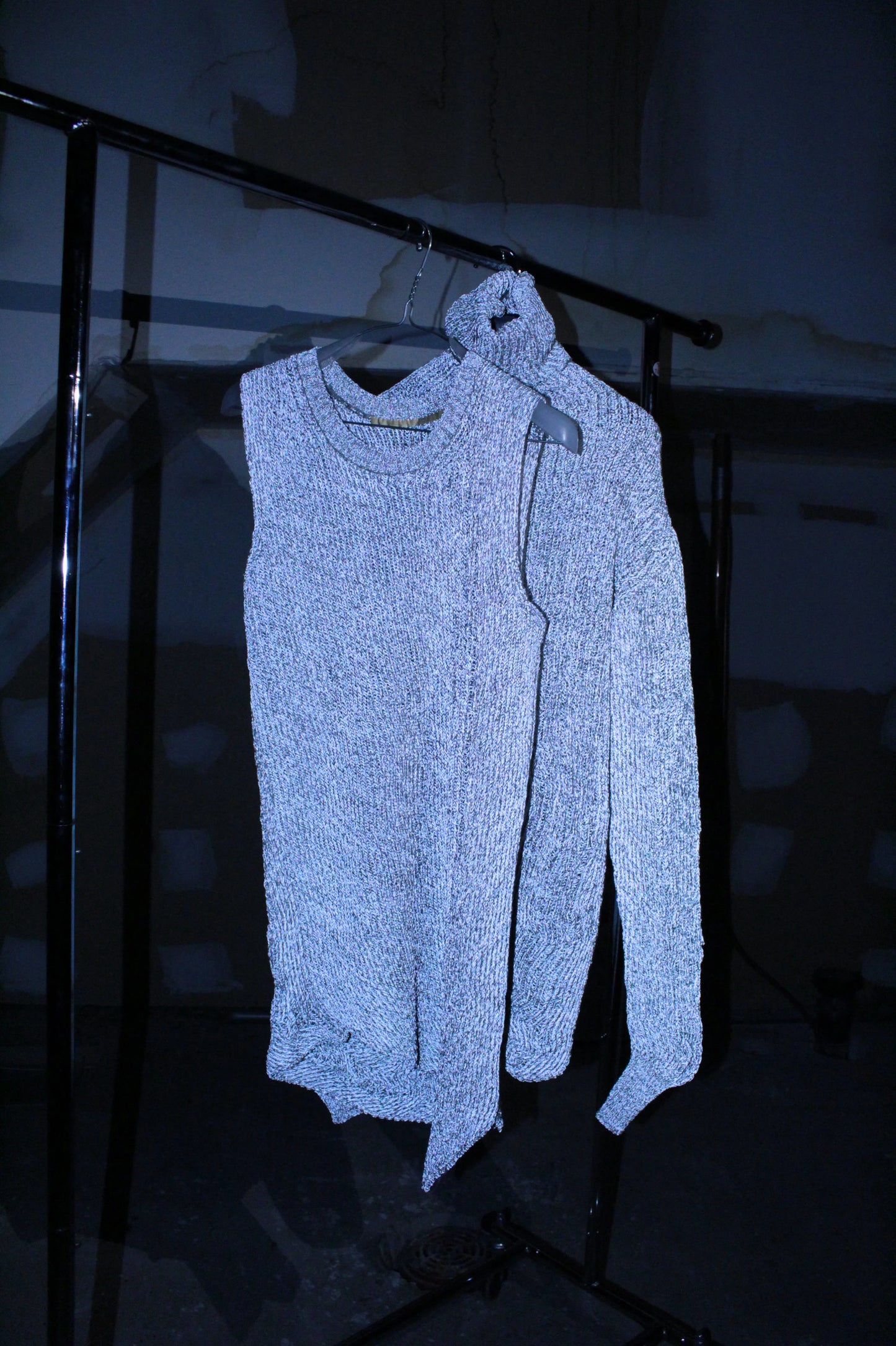 Light blue sweater on a hanger against a dark background