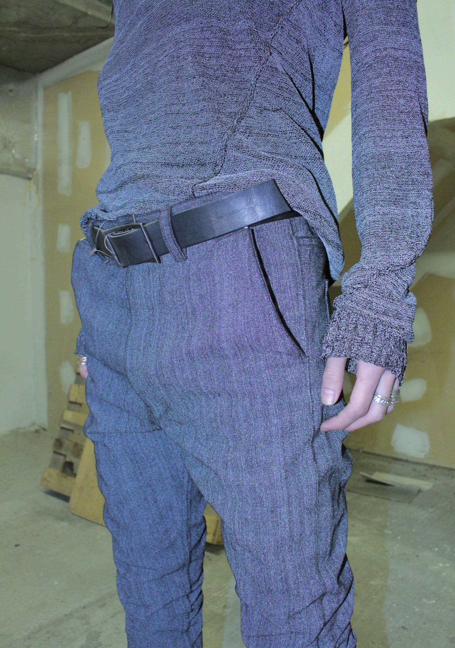 Person wearing a textured gray outfit with a belt and gloves in an indoor setting.