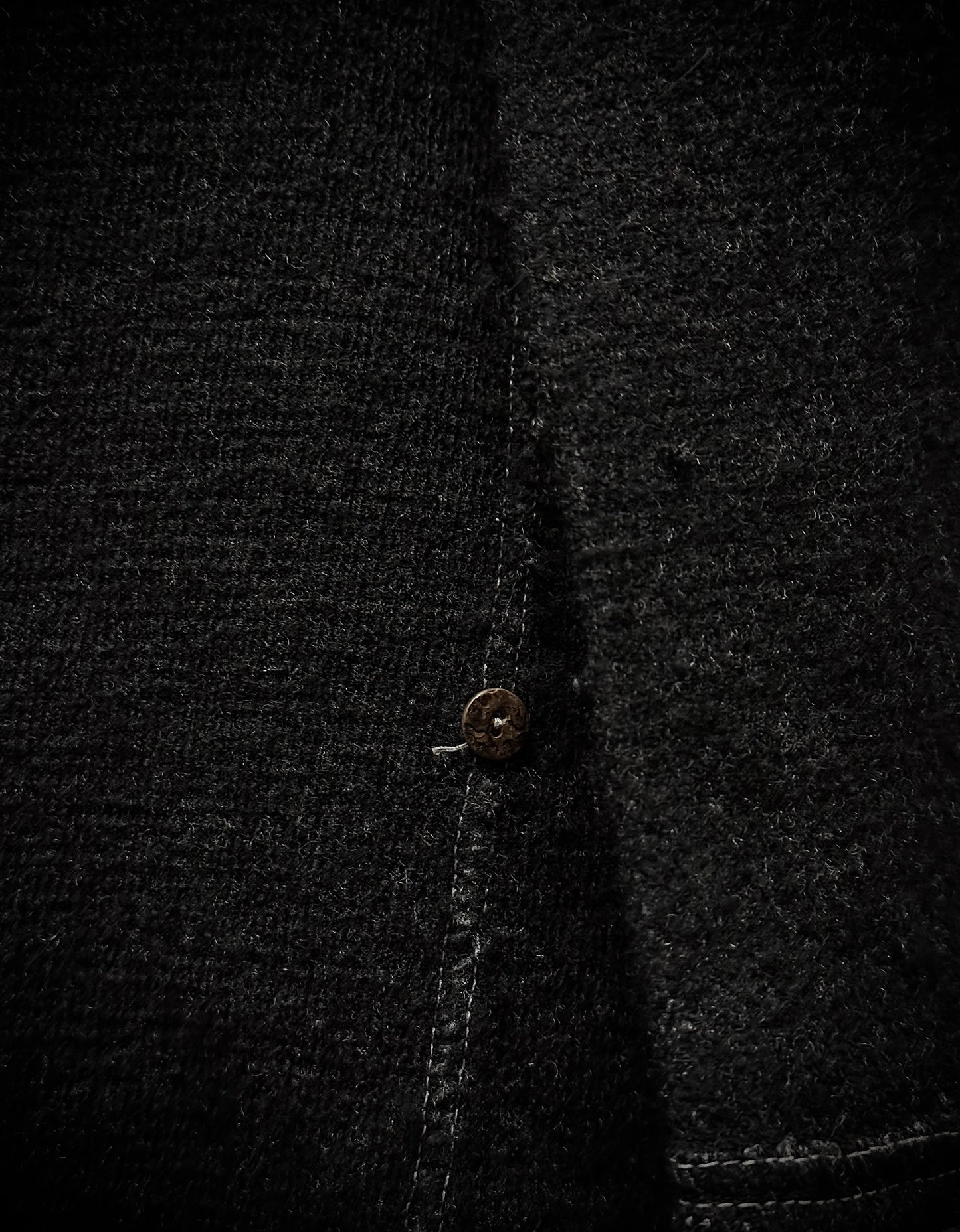 Close-up of a dark textured fabric with a button