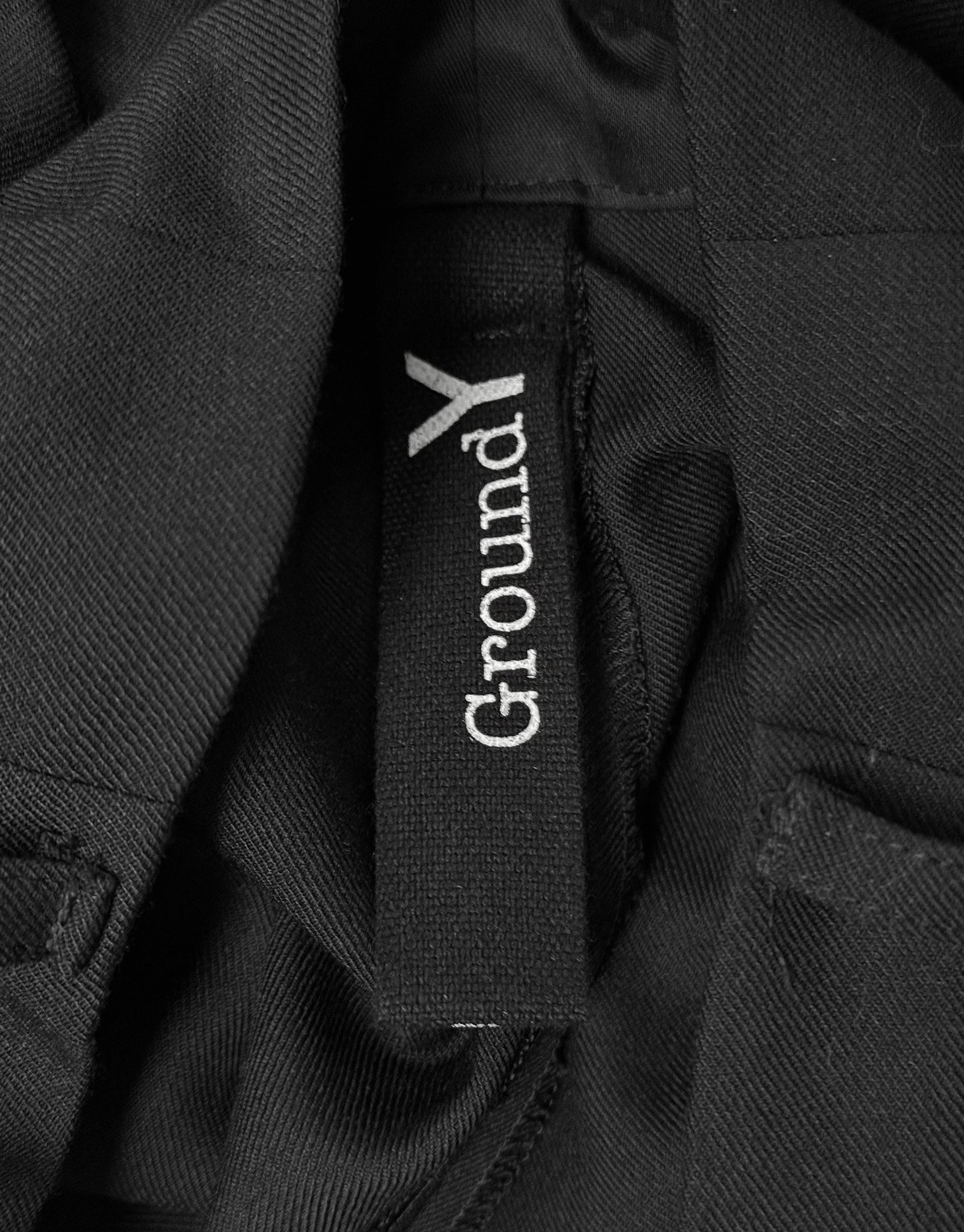 Close-up of a black jacket with 'GroundY' logo on a dark background