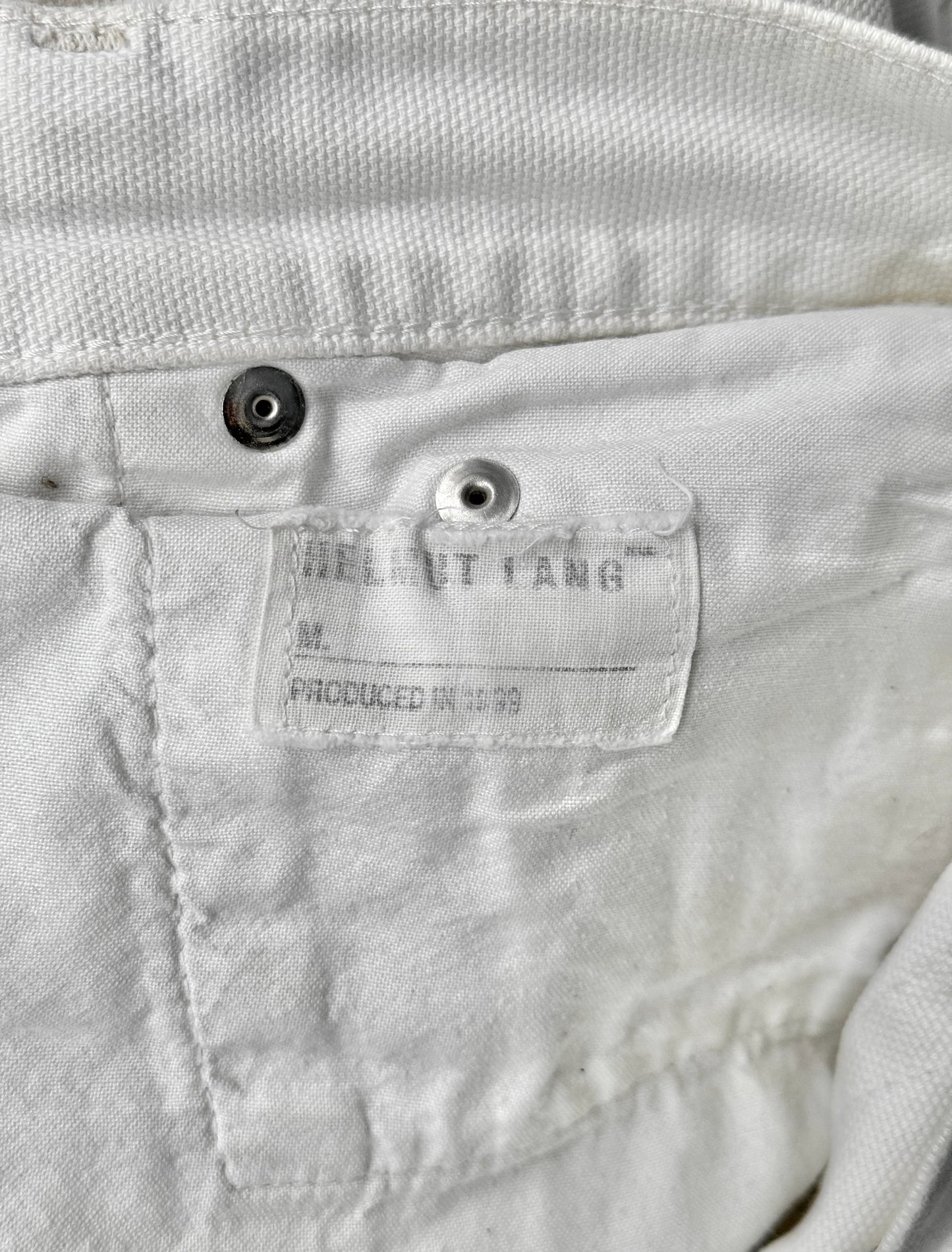 Close-up of a label on a white jacket with 'Helmut Lang' branding.