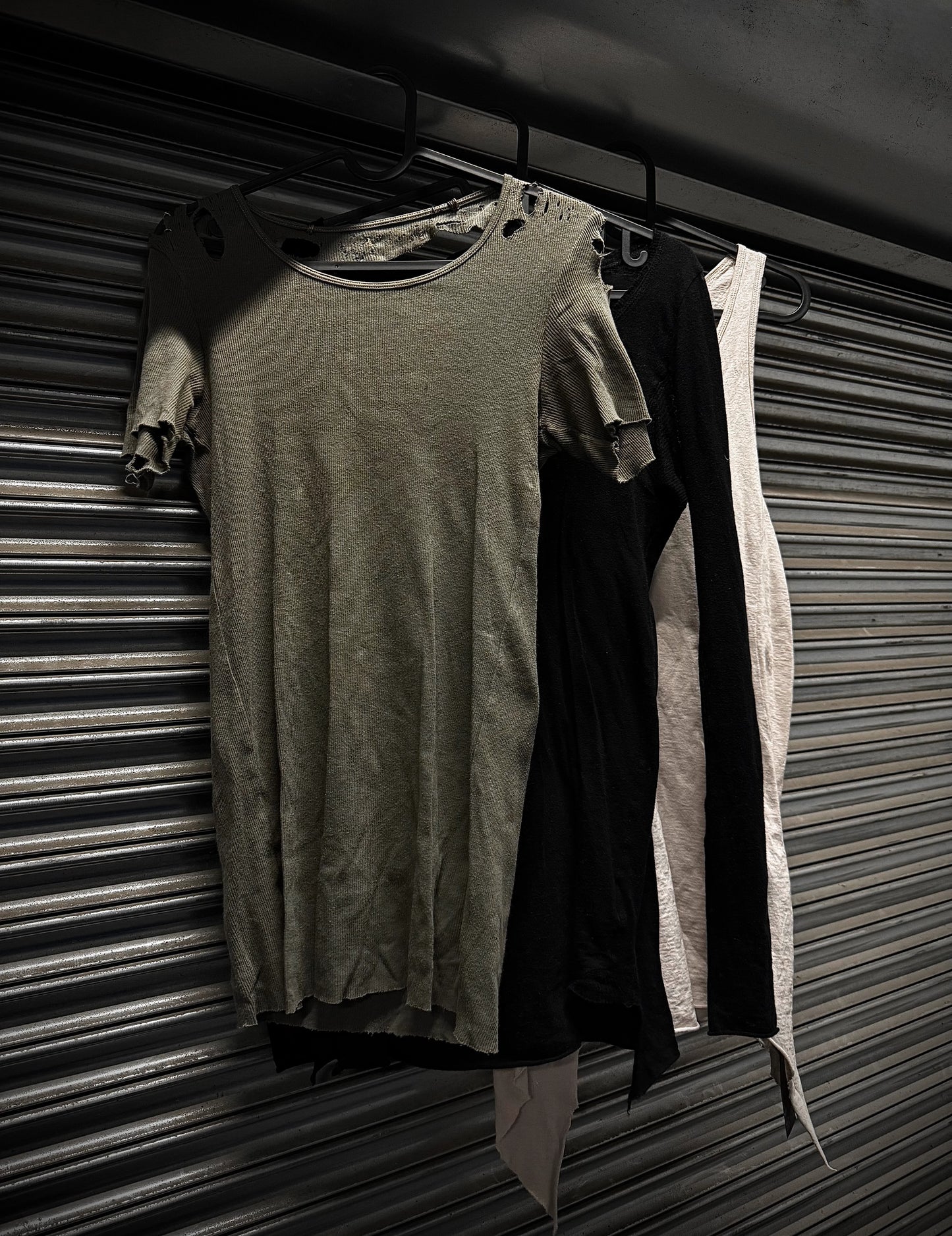 Two dresses hanging on a rack against a metal shutter background