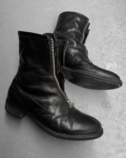 Pair of black leather boots with zippers on a gray surface