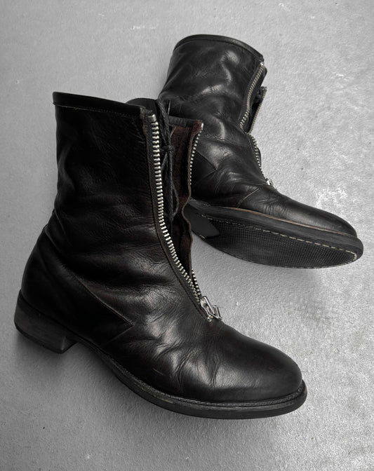 Pair of black leather boots with zippers on a gray surface
