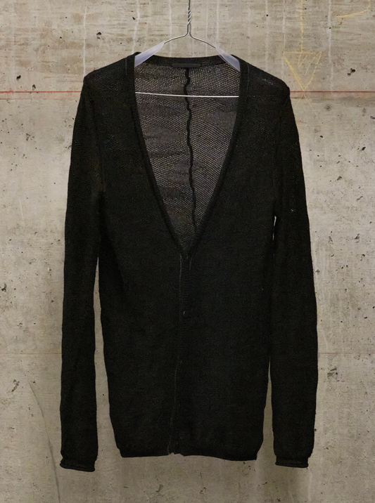 Black cardigan on a hanger against a textured beige wall