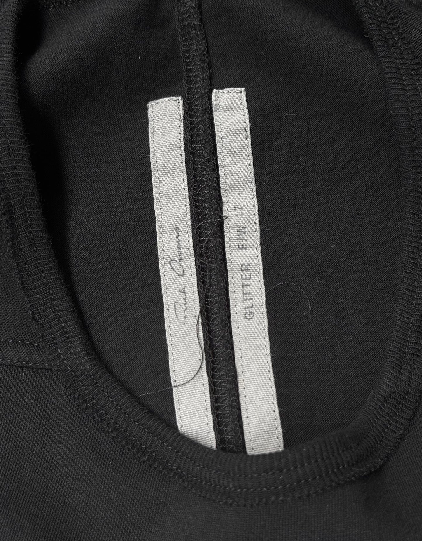 Close-up of a black Rick Owens AW17 “GLITTER” Level Short-sleeves T-shirt collar with two white inner tags—one reading GLITTER FW17 and the other with signature text. Size IT 40, flawless condition.