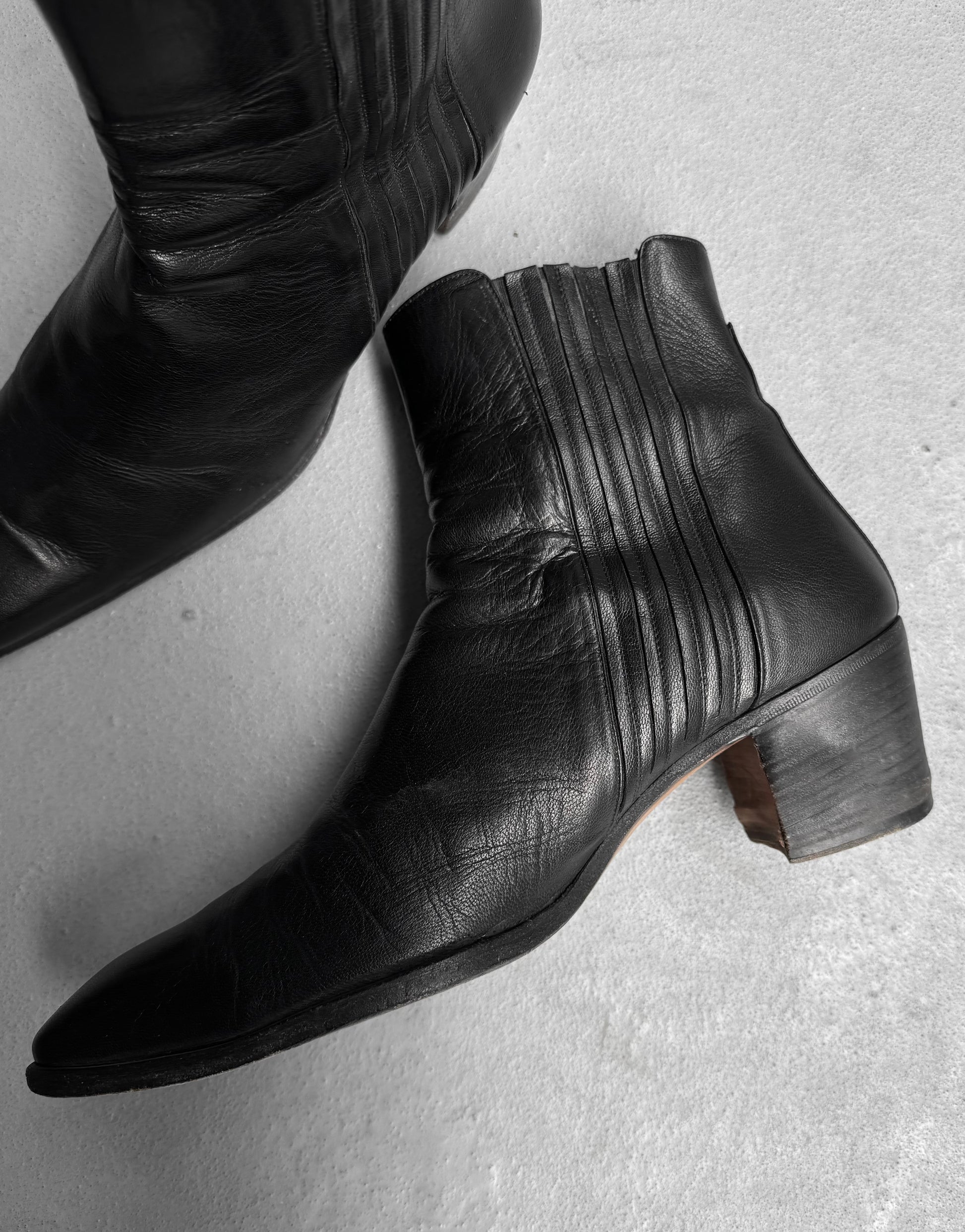 The Saint Laurent Paris YSL Rive Gauche SS04 by Tom Ford 40mm Heel ‘Johnny’ Leather Boots feature black leather, a low chunky heel, and vertical stitching, echoing the refined style of iconic Yves Saint Laurent heeled boots.