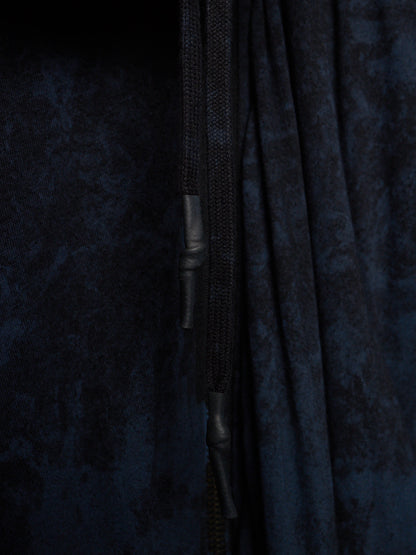 Close-up of a dark navy blue textured fabric garment with a black drawstring and black zipper pull.