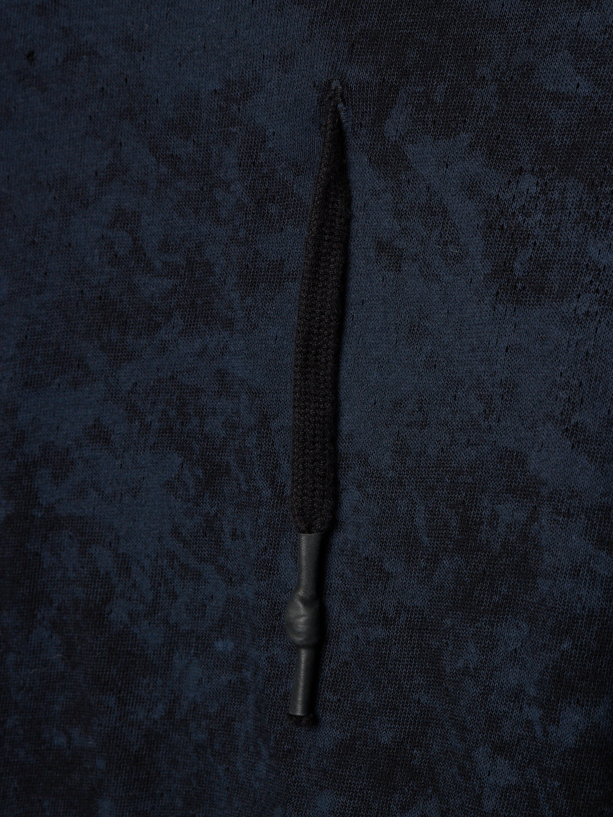 A single black braided cord or strap with a dark metal connector, laid vertically against a dark textured fabric background.