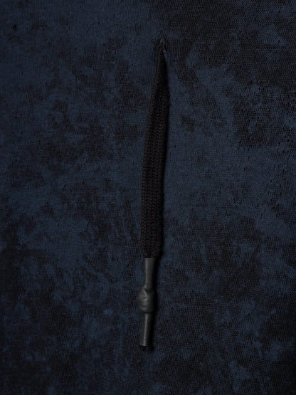 A single black braided cord or strap with a dark metal connector, laid vertically against a dark textured fabric background.