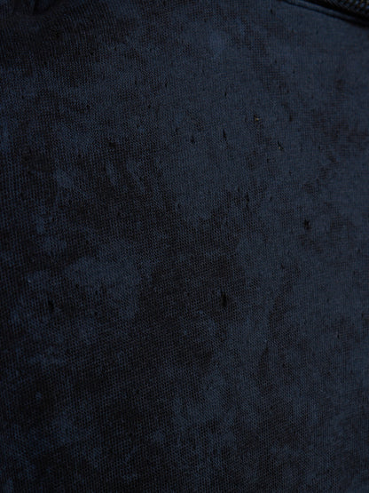 A close-up of a dark navy blue textured fabric surface with a subtle mottled or distressed pattern.