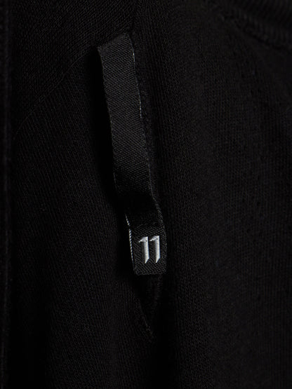 Close-up of a black knit garment featuring a black fabric tab with a small white '11' printed on it.