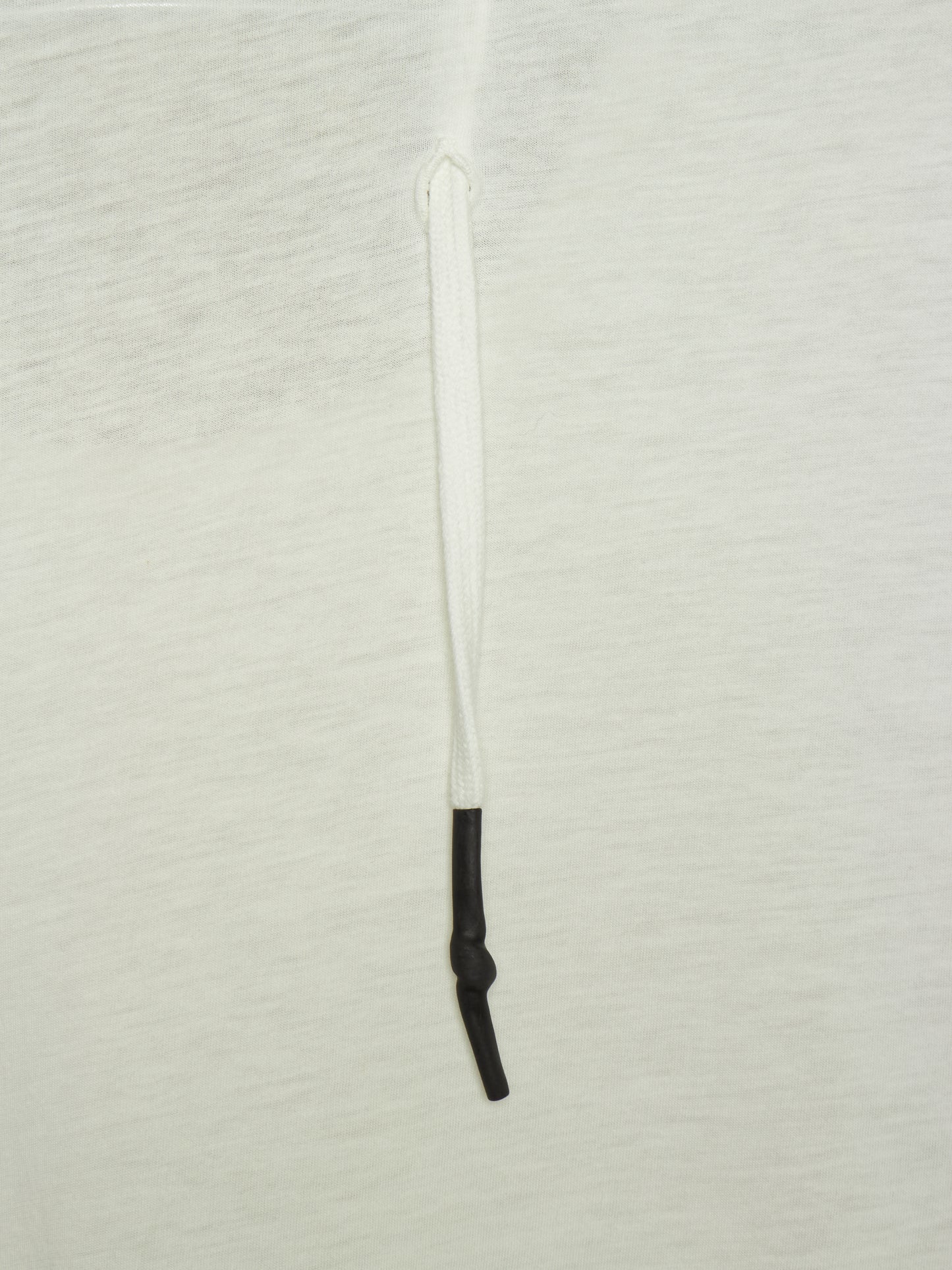 A close-up of a white textured fabric surface with a vertical white drawstring or cord running down the center, ending in a black knotted section near the bottom.