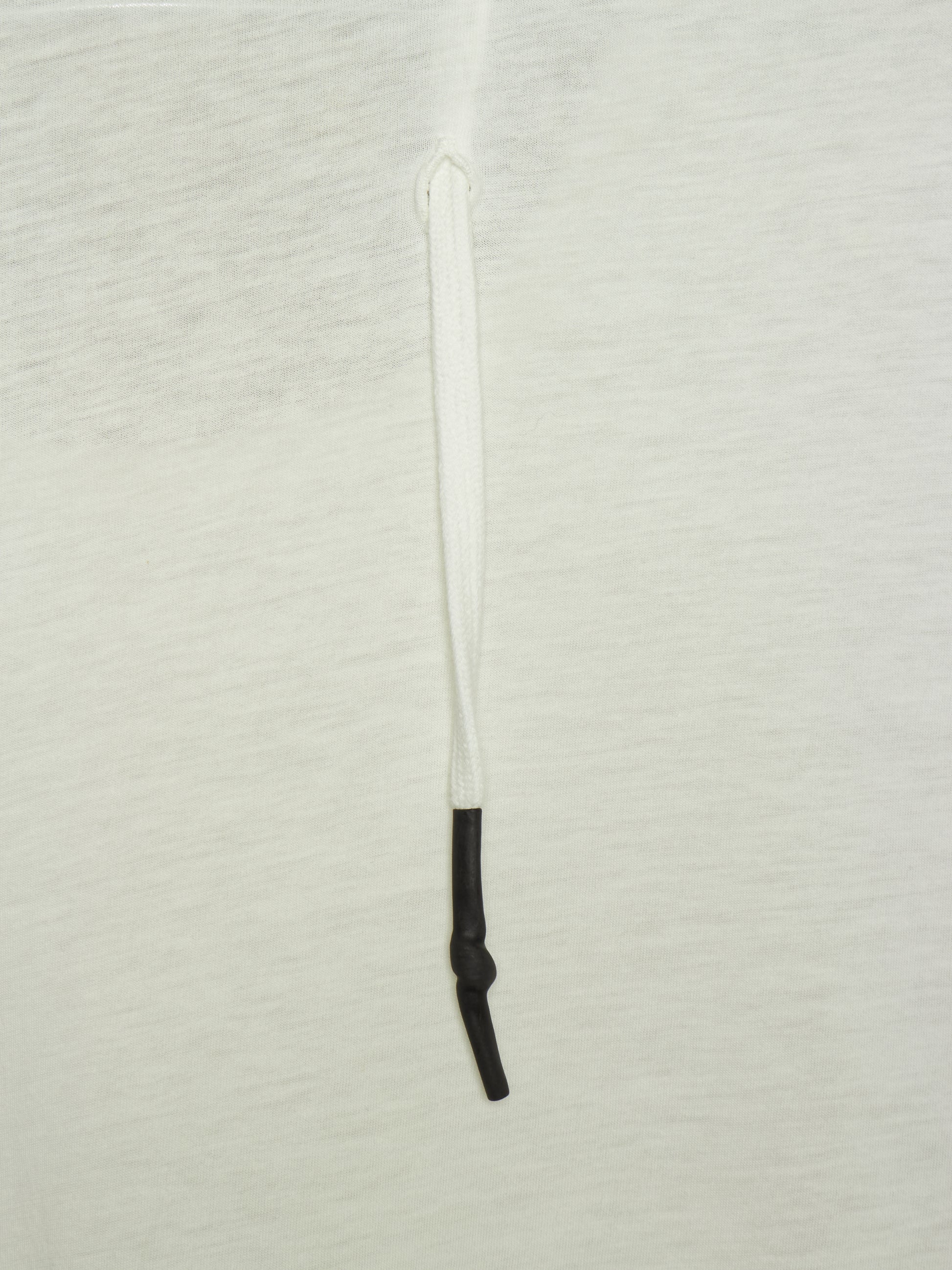 A close-up of a white textured fabric surface with a vertical white drawstring or cord running down the center, ending in a black knotted section near the bottom.