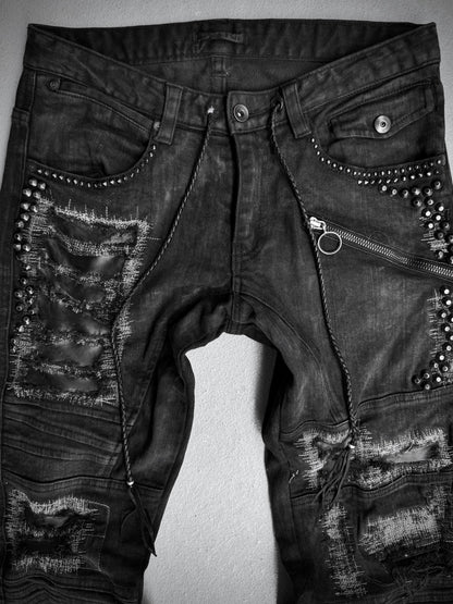 KMRii Early 00s Goatskin Patches Studded Crush Flare-zip Denim—black jeans featuring distressed details, fading, metal studs, horizontal zipper above one pocket, frayed patches, and decorative stitching. Size 2 (US 29-30 waist).