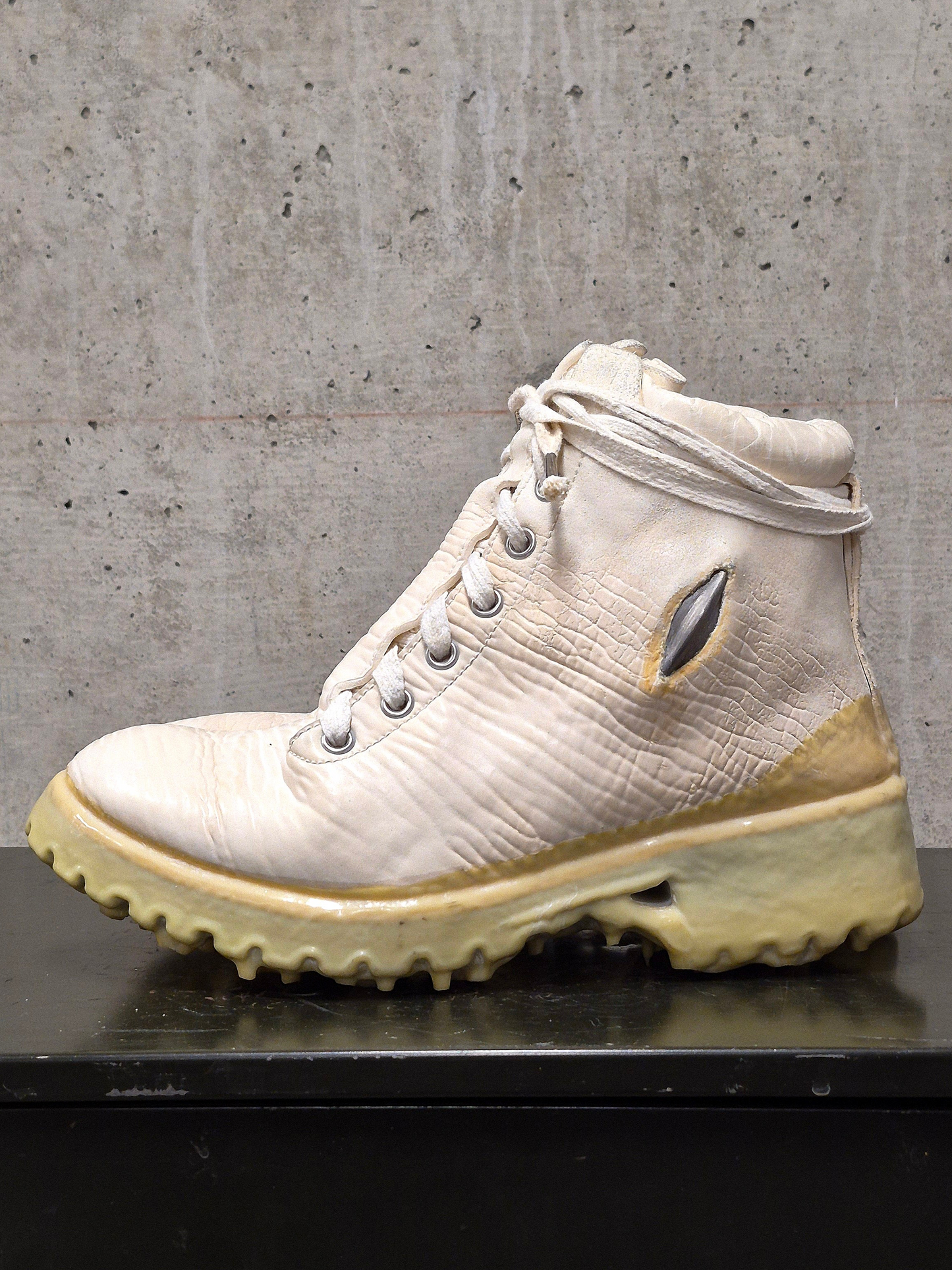 White hiking boot with beige sole on a concrete surface