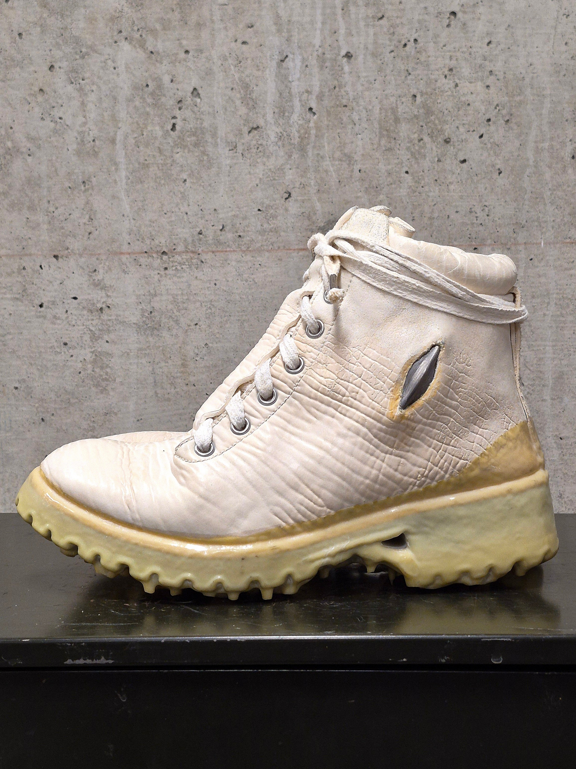 White hiking boot with beige sole on a concrete surface