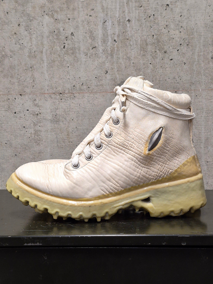 White hiking boot with beige sole on a concrete surface